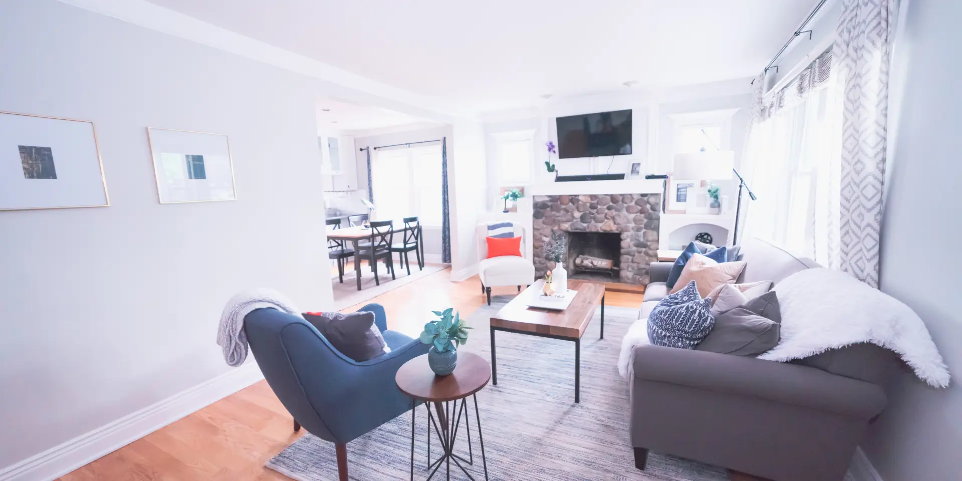Salon moderne avec canapé gris, fauteuil bleu, table basse en bois et cheminée