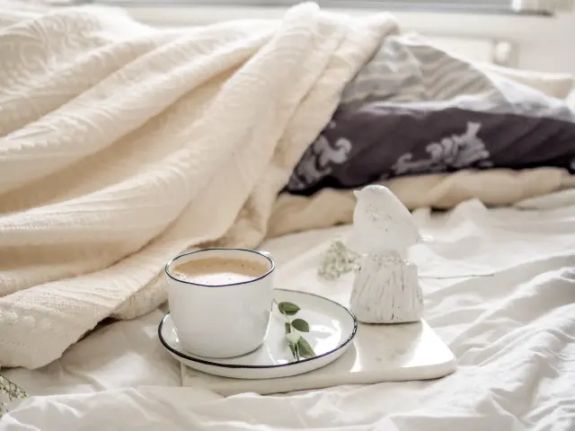 Une tasse de café sur un plateau avec des feuilles et une sculpture en forme de montagne