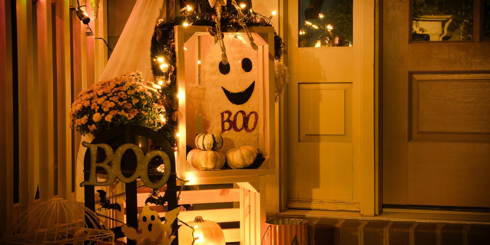 Décorations Halloween avec citrouilles, squelette et guirlandes lumineuses devant une porte