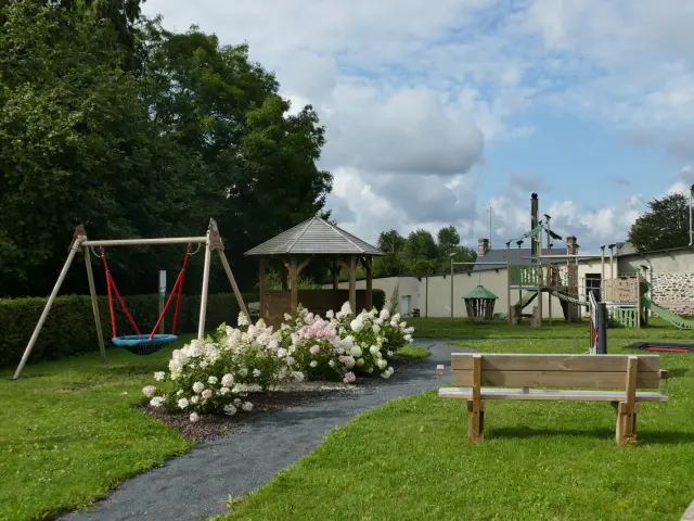 Aire de jeux avec balançoire, banc et structure à Courcy