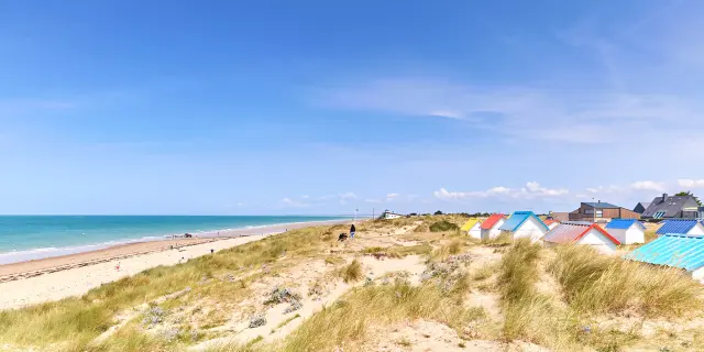 Sandstrand mit bunten Strandhütten und dem Ozean im Hintergrund
