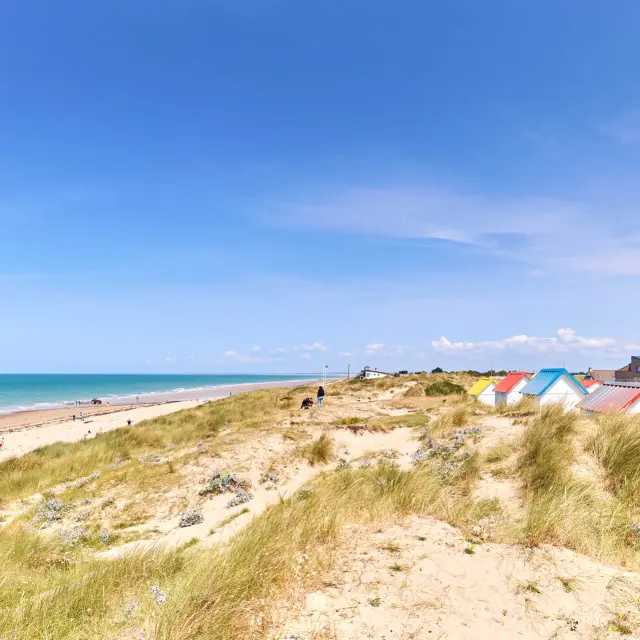 Sandstrand mit bunten Strandhütten und dem Ozean im Hintergrund