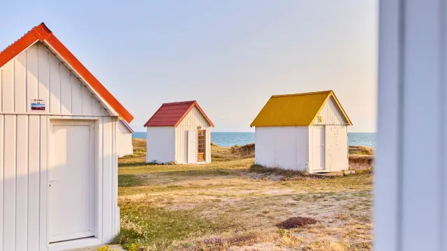 Trois cabines de plage avec des toits de couleurs différentes à Gouville sur Mer