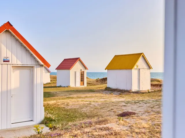 Trois cabines de plage avec des toits de couleurs différentes à Gouville sur Mer