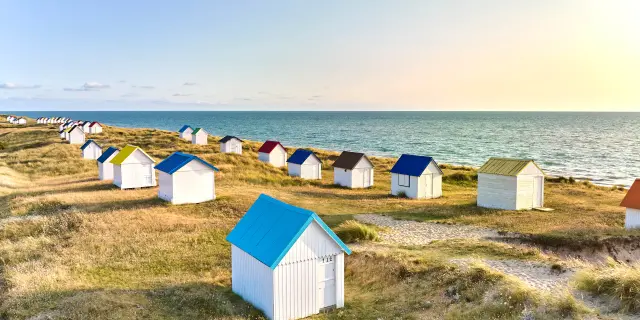Bunte Strandhütten in einer Reihe auf einer Düne am Meer