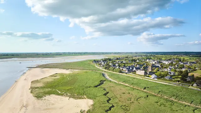 Vue aérienne d'un village côtier avec une plage déserte et des terres agricoles