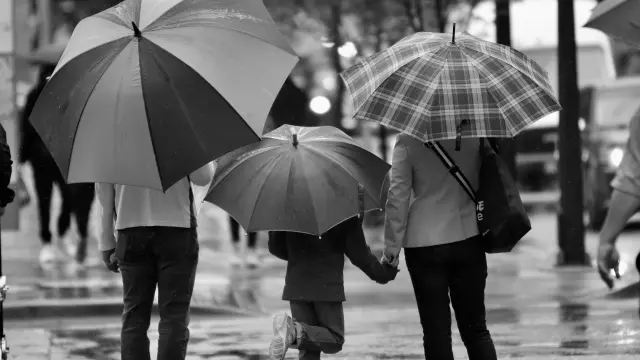 Une famille marche sous la pluie avec des parapluies
