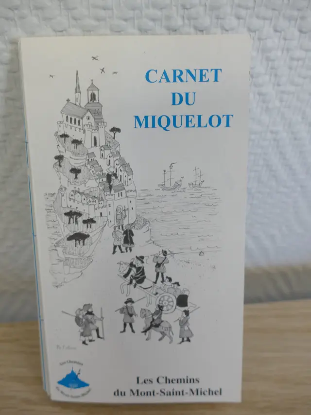Couverture d'un carnet illustré avec un dessin de Mont-Saint-Michel et des pèlerins : Carnet du Miquelot