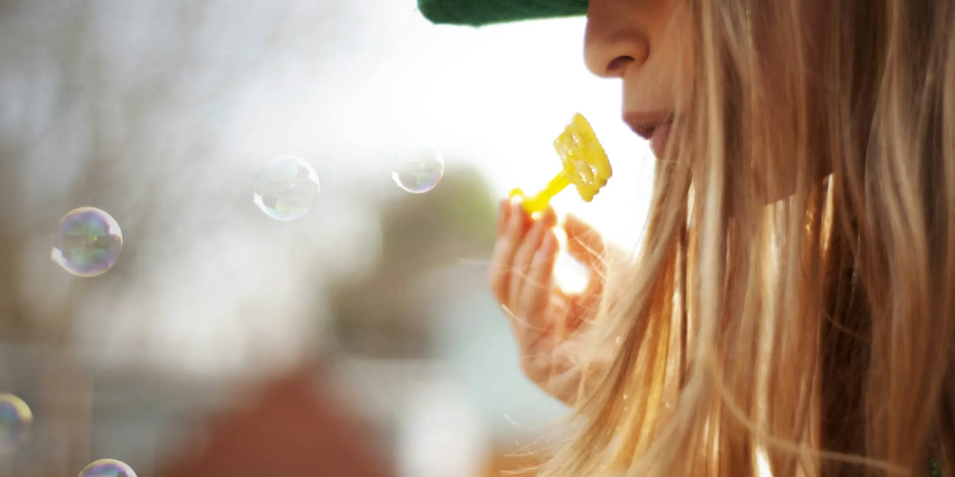 Enfant avec un chapeau vert soufflant des bulles de savon
