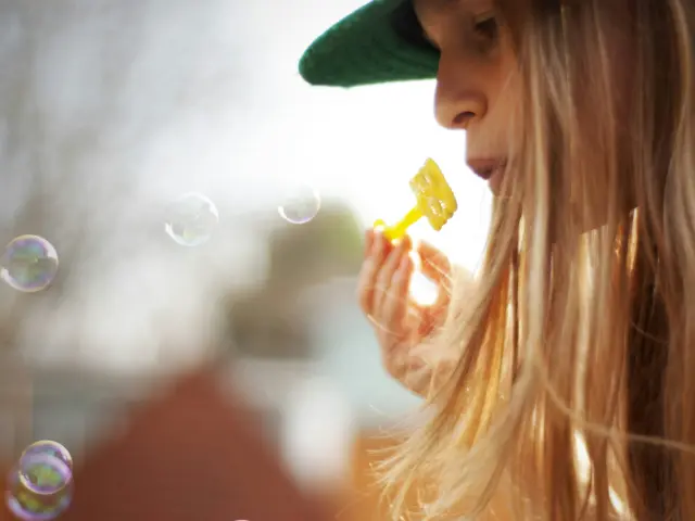 Enfant avec un chapeau vert soufflant des bulles de savon