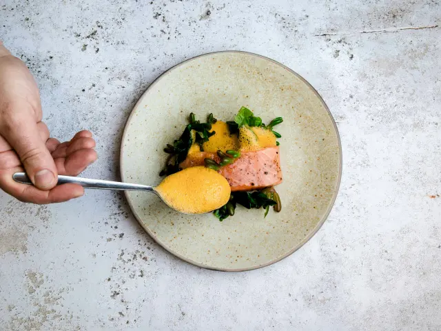 Assiette avec un plat composé de poisson, de purée de patate douce et de légumes verts