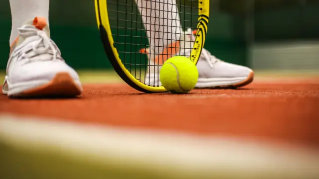 Pieds d'un joueur de tennis avec raquette et balle