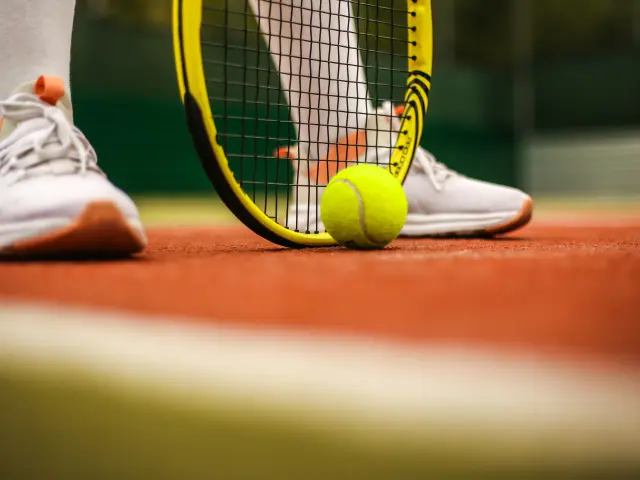 Pieds d'un joueur de tennis avec raquette et balle
