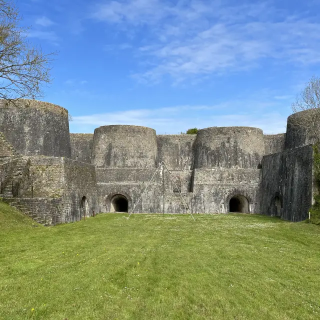 Anciennes ruines en pierre avec arcs et tours, entourées d'une prairie