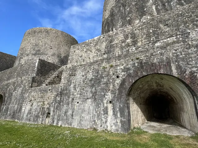 Stone wall of a medieval fortress with an arch and turrets