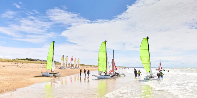 Voiliers avec des voiles vertes sur une plage de sable