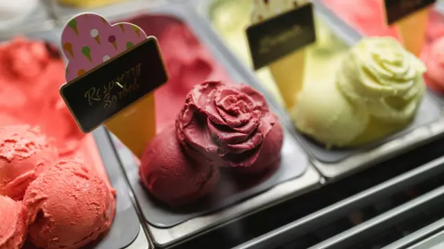 Boule de glace à la fraise posée sur une gaufre croustillante avec un cornet de glace à la vanille en arrière-plan