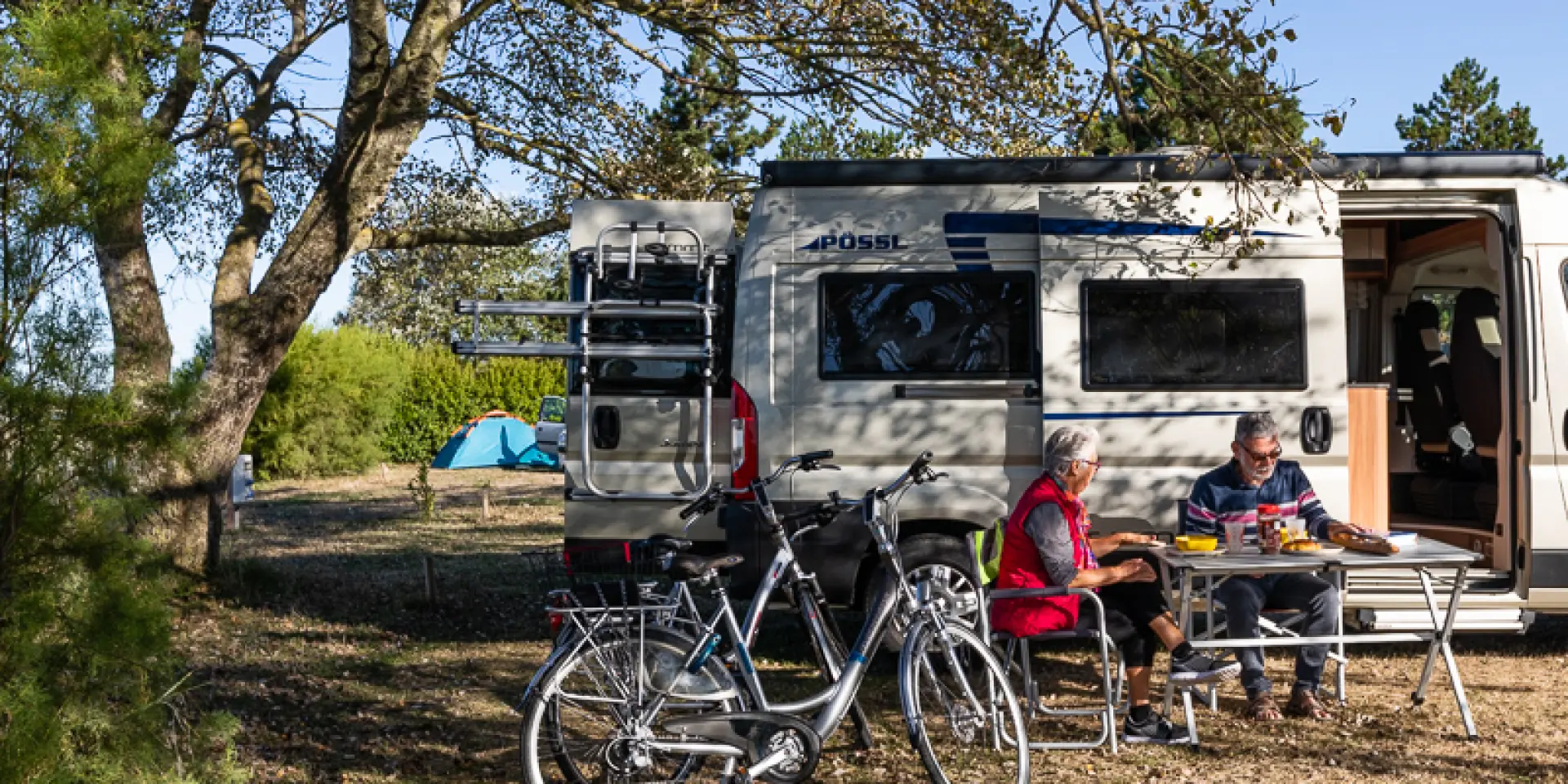 Deux personnes assises devant un camping-car avec des vélos