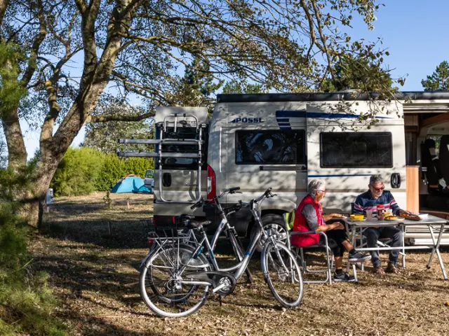 Deux personnes assises devant un camping-car avec des vélos