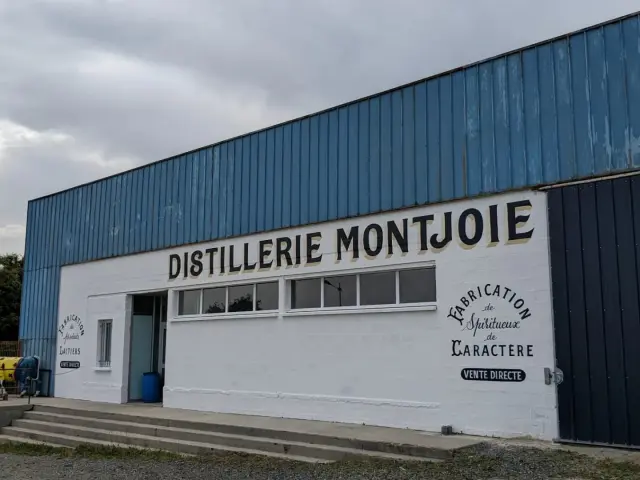 Bâtiment industriel de la distillerie Montjoie avec logo et texte en français