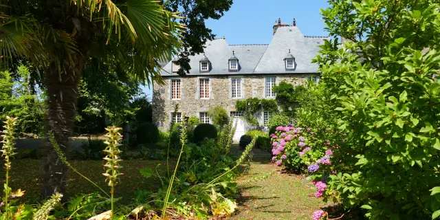 Maison en pierre avec volets blancs et jardin fleuri au crépuscule