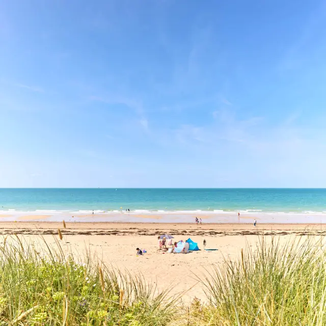 Plage avec voiliers amarrés et personnes se relaxant sur le sable