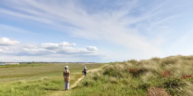 Une famille marche sur un sentier dans les dunes à Blainville Sur Mer