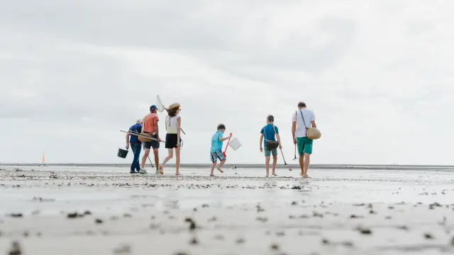 Quatre personnes marchant sur une digue au crépuscule avec des voiliers amarrés en arrière-plan