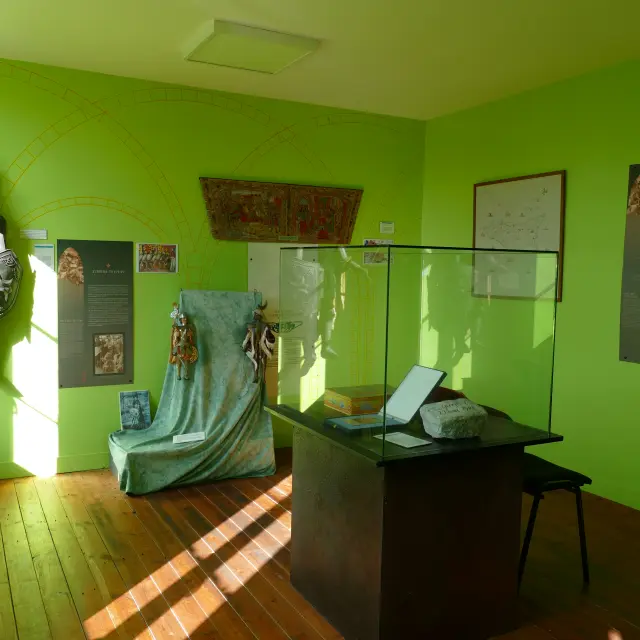 Salon vert avec un canapé, une table basse, une statue, des cadres muraux et des plantes