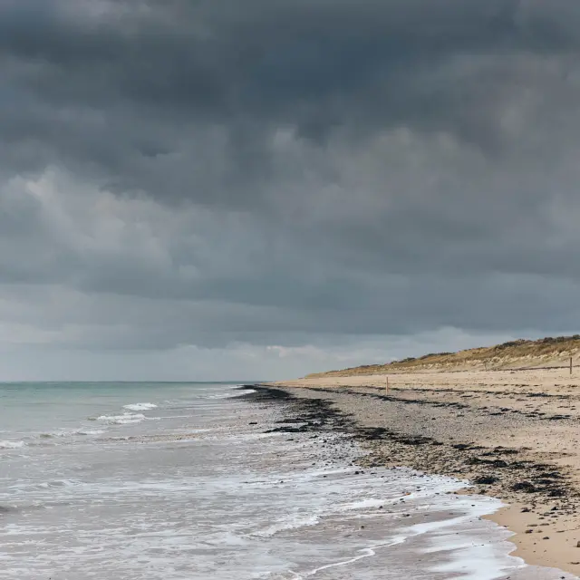 Strand mit Wellen und bewölktem Himmel