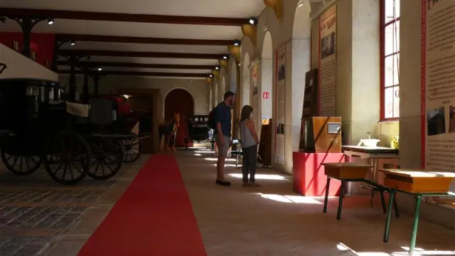 People visiting a museum with exhibits and an old carriage