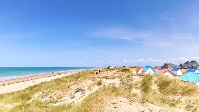 Sandstrand mit bunten Strandhäuschen und dem Ozean im Hintergrund