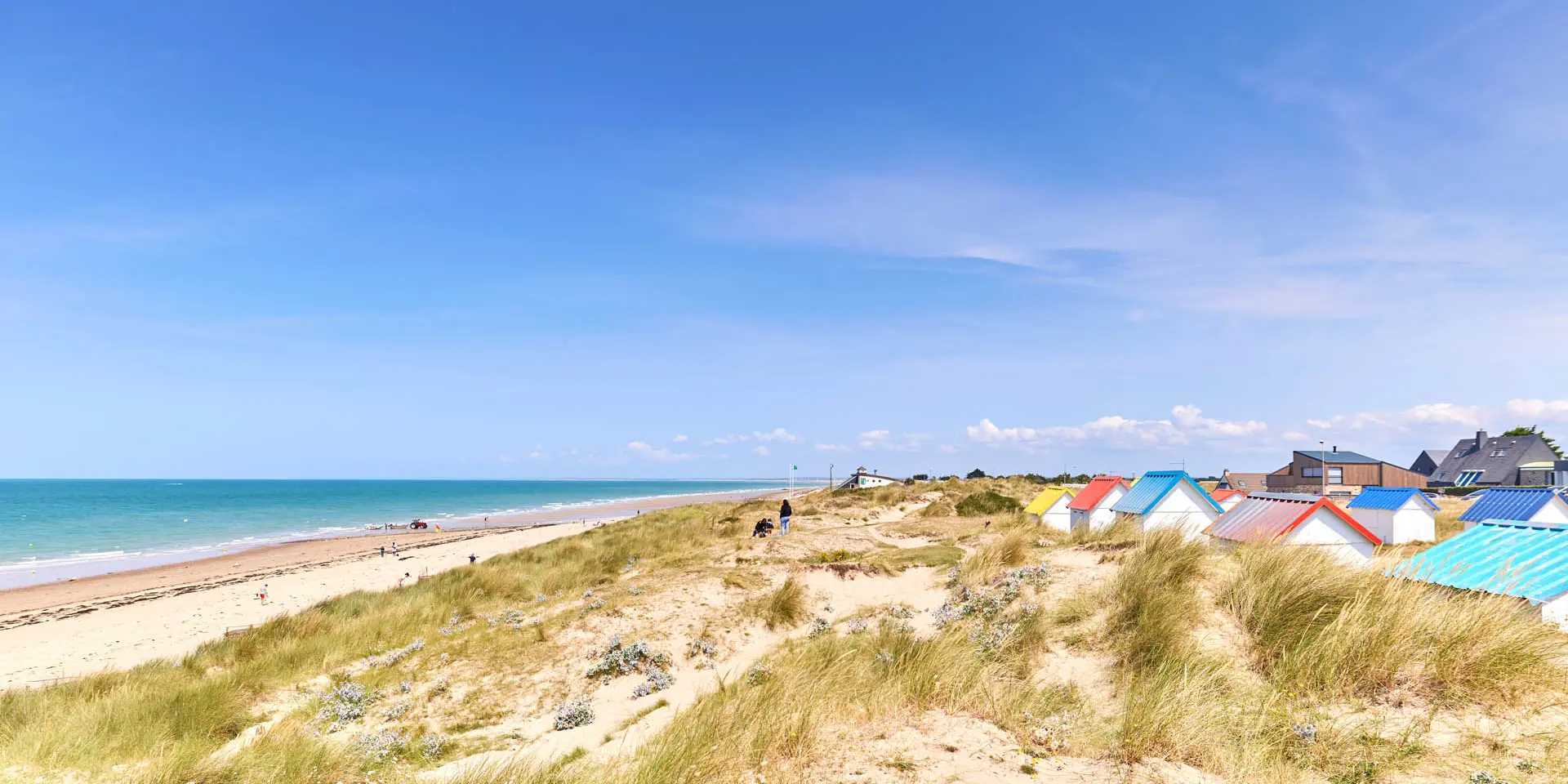 Sandy beach with colorful beach huts and the ocean in the background