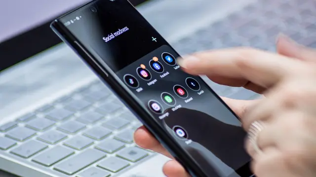 Main tenant un smartphone affichant des icônes d'applications sociales