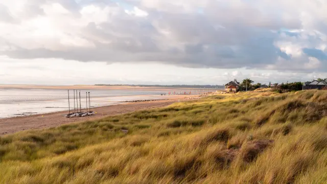 Port avec des voiliers amarrés et des bâtiments en arrière-plan sous un ciel nuageux au crépuscule