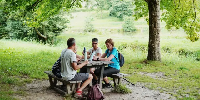 Trois personnes assises à une table de pique-nique en randonnée
