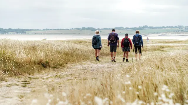 Quatre personnes marchant sur un sentier en bord de mer