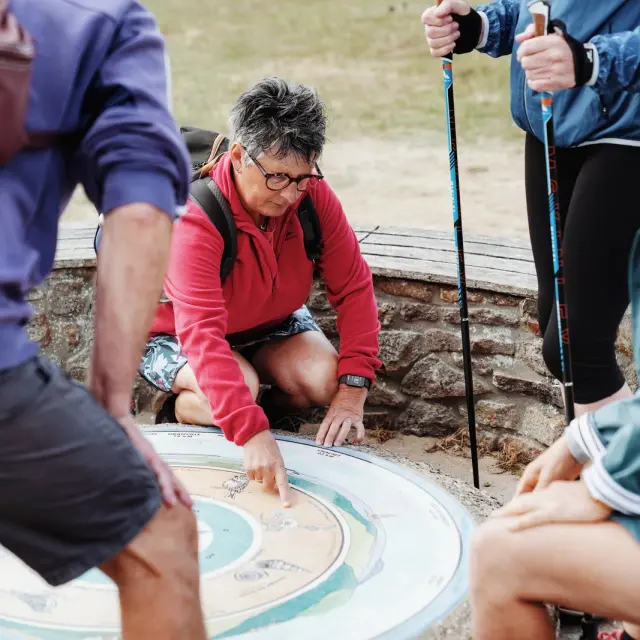 A group of hikers examining a map on an outdoor bench