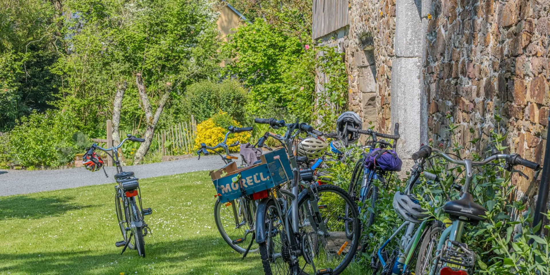 Several bikes and motorcycles parked on a grassy sidewalk by the road, with a visible advertisement banner