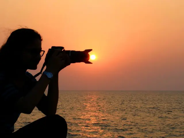 Une personne prend une photo du coucher de soleil sur la plage