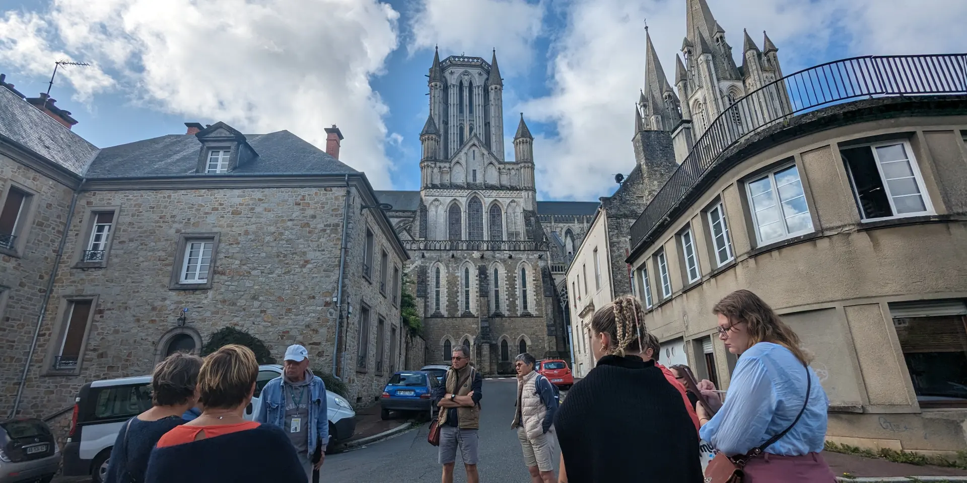 Groupe de personnes écoutant un guide devant la cathédrale de Coutances
