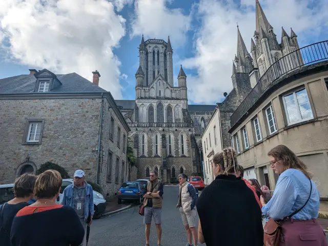 Rues piétonnes animées devant une cathédrale gothique avec des passants et des voitures garées