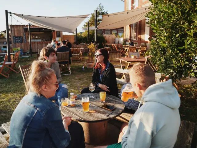 Groupe d'amis assis autour d'une table en bois en terrasse à la petite Gare de Regnéville sur Mer