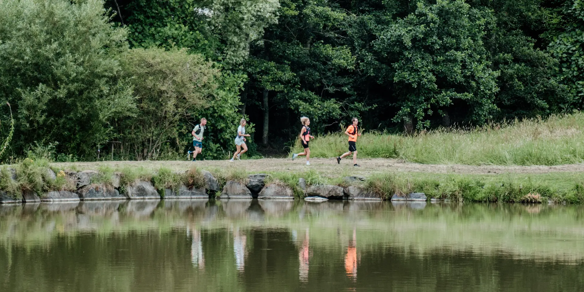 Quatre personnes courant le long d'un lac entouré d'arbres : trail, course à pied