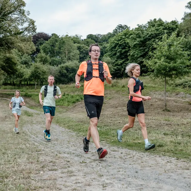 Quatre personnes courent sur un chemin de terre en pleine nature