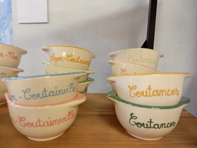 Bols empilés avec des noms de villes de Coutances mer et bocage écrits dessus