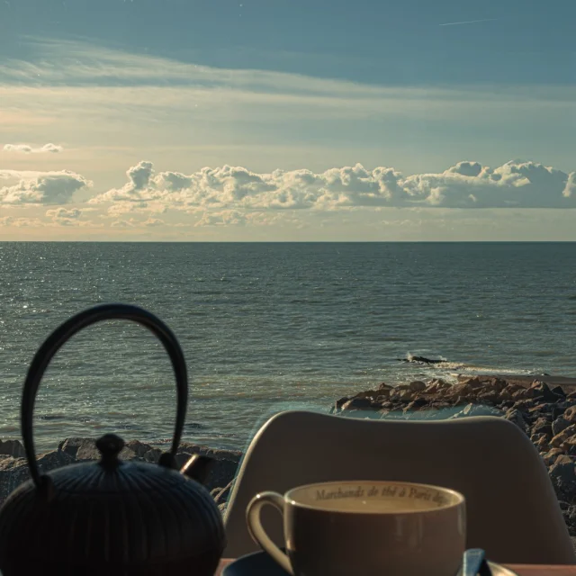 Une tasse de thé et une théière sur une table près de la mer