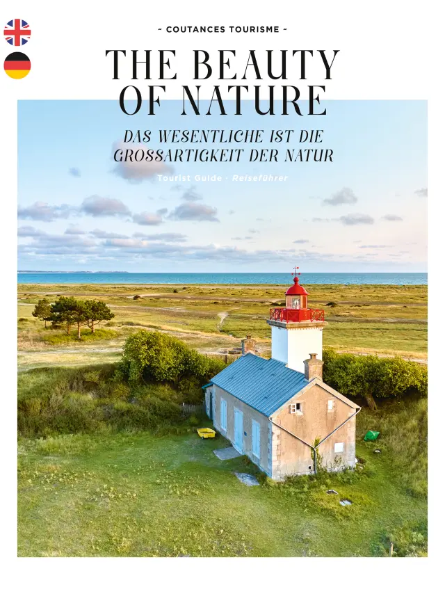 Red and white lighthouse surrounded by greenery, with a blue-roofed blue house in the background, near a body of water
