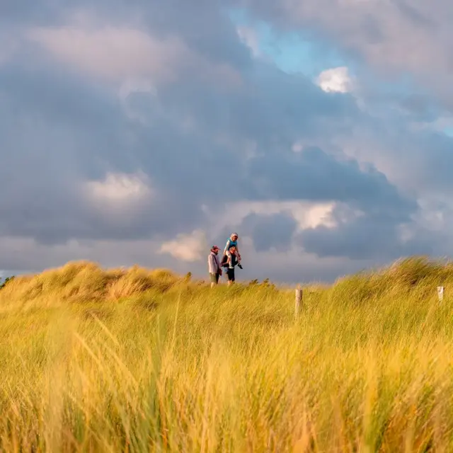 Deux personnes debout sur une dune avec un coucher de soleil en arrière-plan