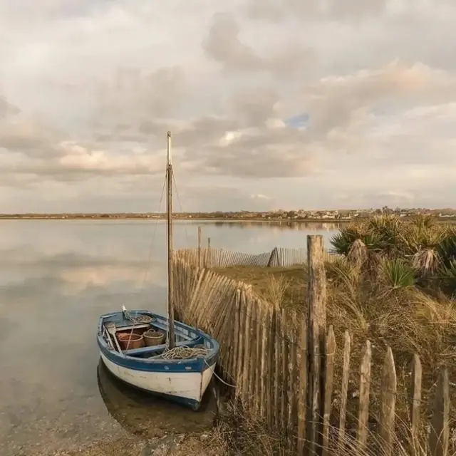 Deux voiliers amarrés sur une plage au coucher du soleil, avec un ciel nuageux en arrière-plan